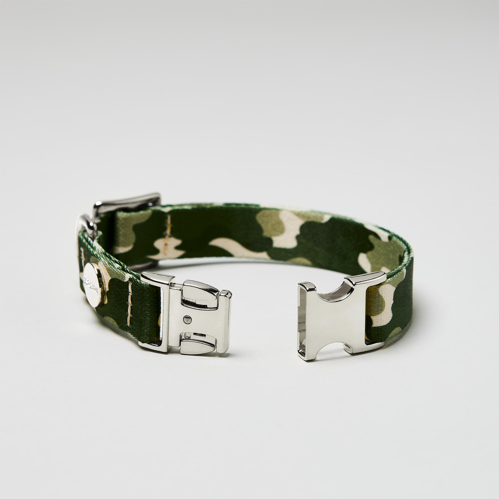 Detailaufnahme verstellbares Hundehalsband „Entdecker“ mit offener silberfarbener Steckschließe, tarnfarbenes Gurtband.