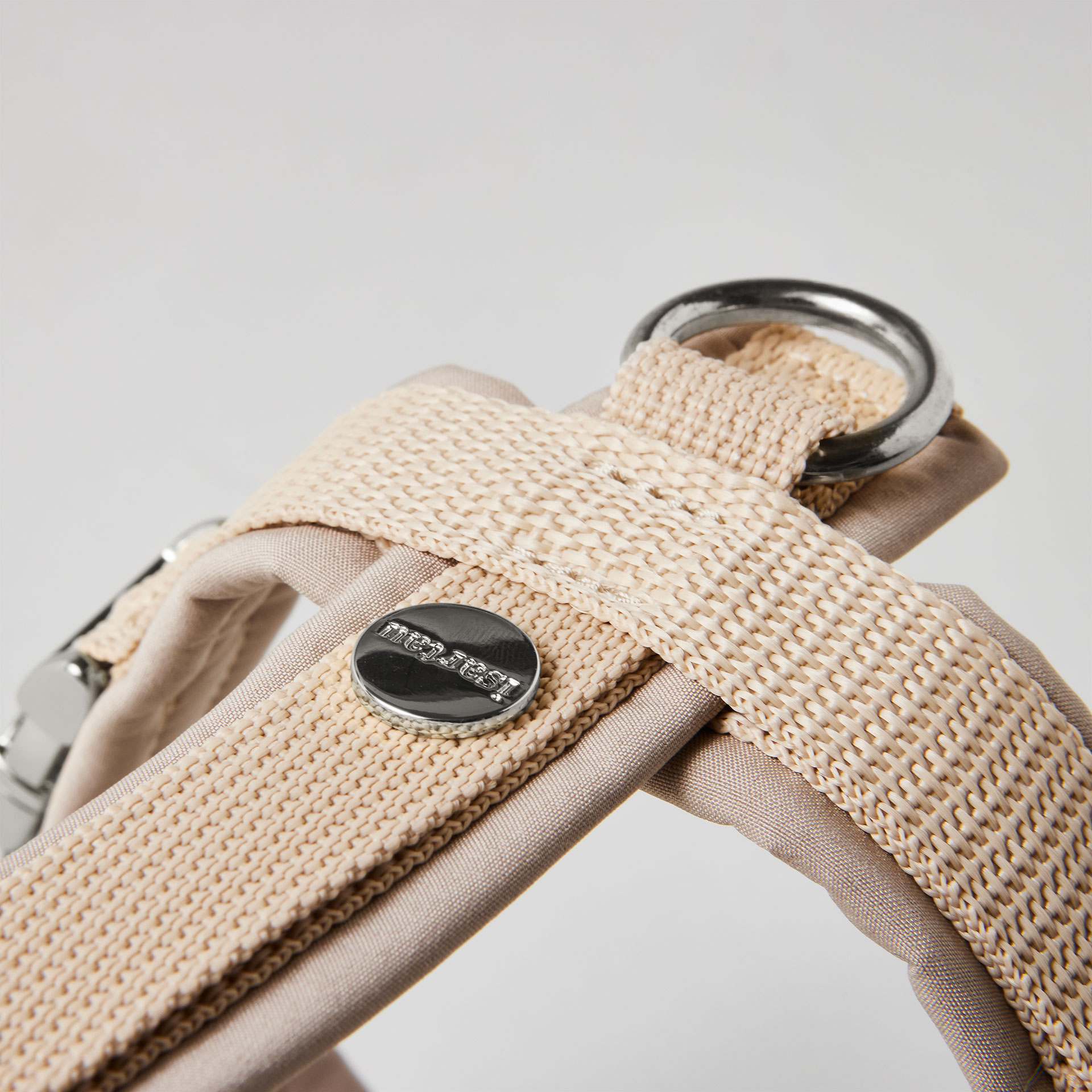Rückenstück des beigen Hundegeschirrs mit gepolstertem O-Ring zum Einhaken des Karabiners und Logo-Niete