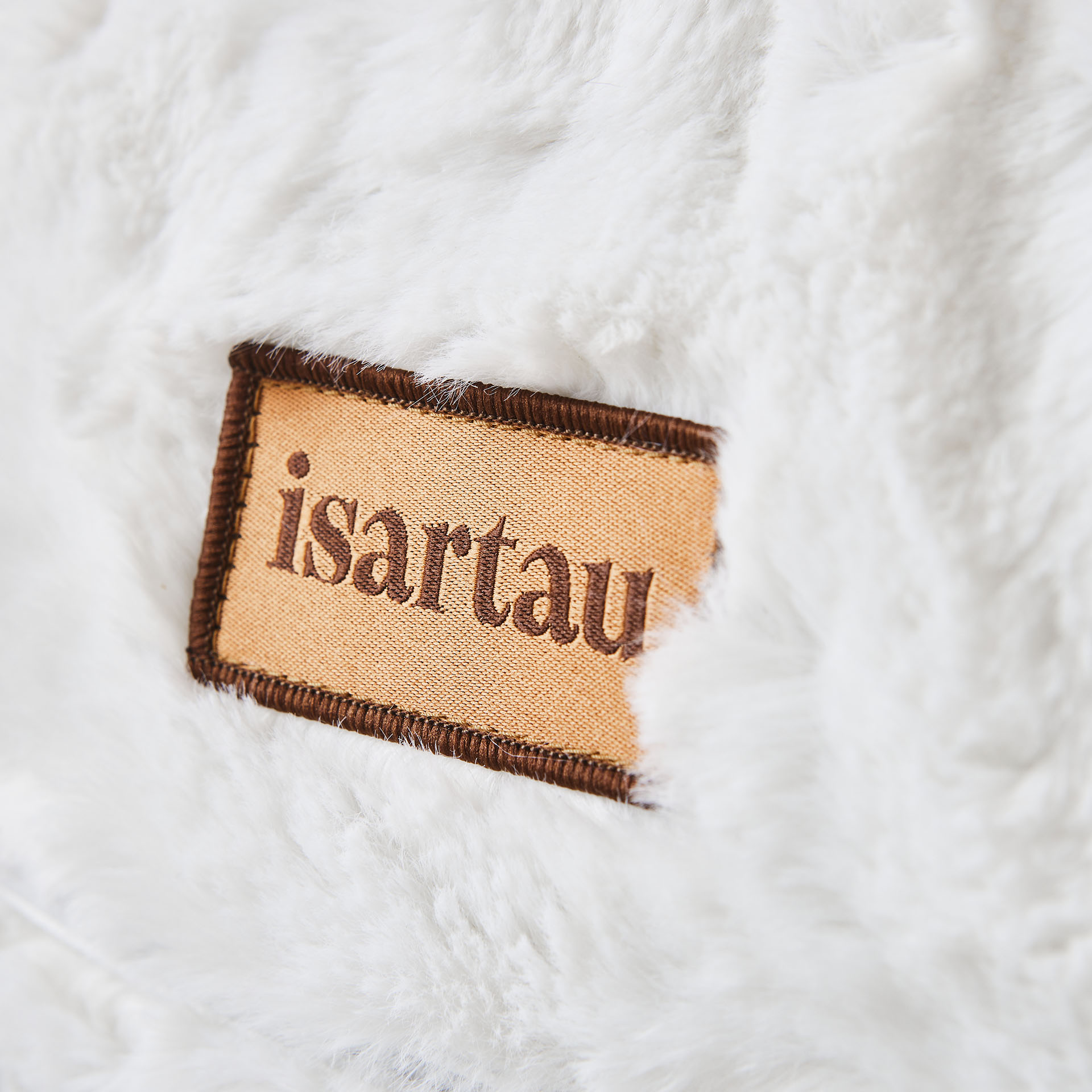 Detail Hundebett Bagelbettchen mit abnehmbaren wollweißen Kunstfellbezug, Fokus auf isartau Logo