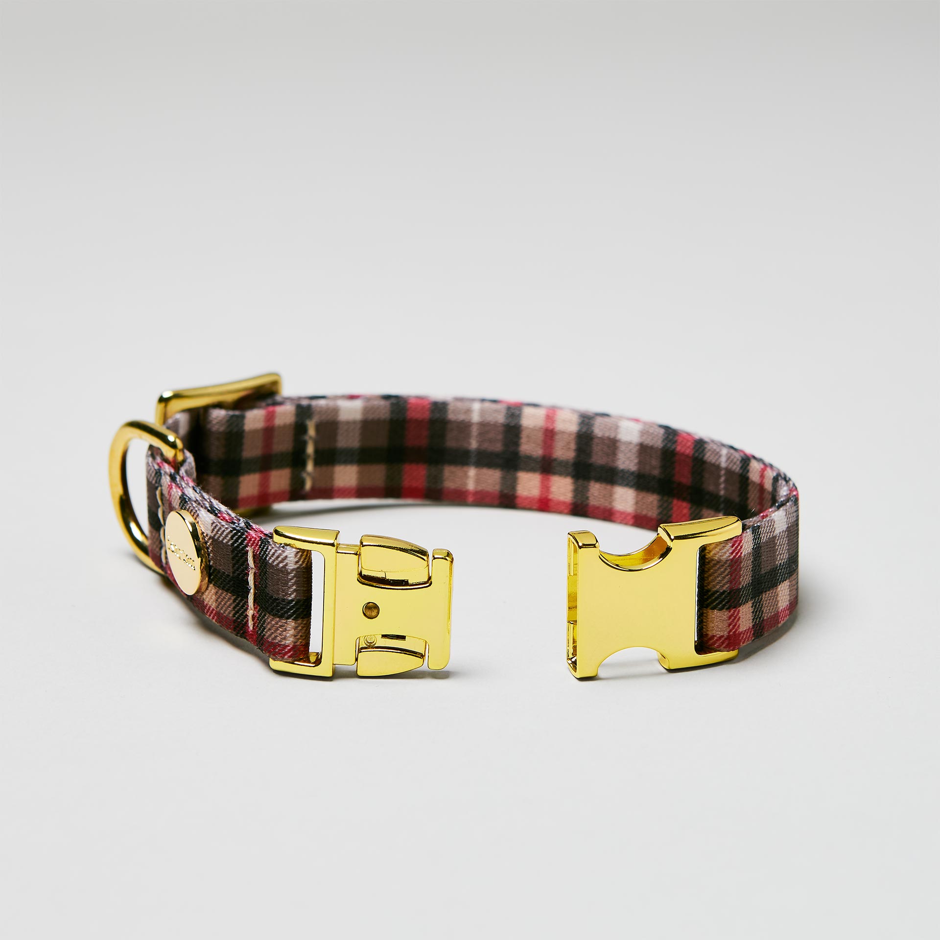 Detailaufnahme verstellbares Welpenhalsband „Flaneur“ mit offener goldfarbener Steckschließe, Gurtband mit Karo-Print.