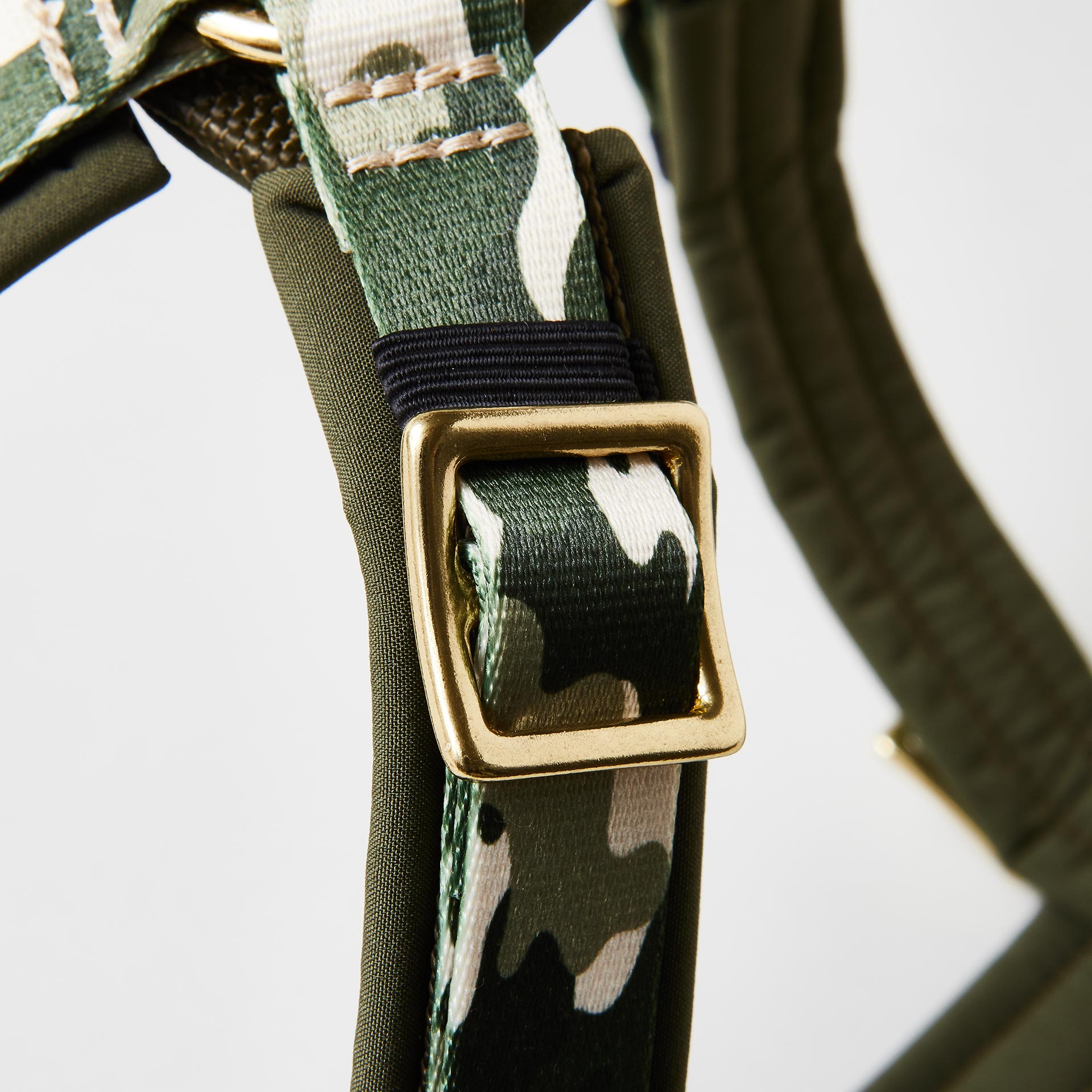 Detail verstellbares gepolstertes Hundegeschirr „Entdecker“ mit goldfarbenem Gurtbandschieber zur Größenanpassung und Camouflage-Gurtband in Grün und Beige.