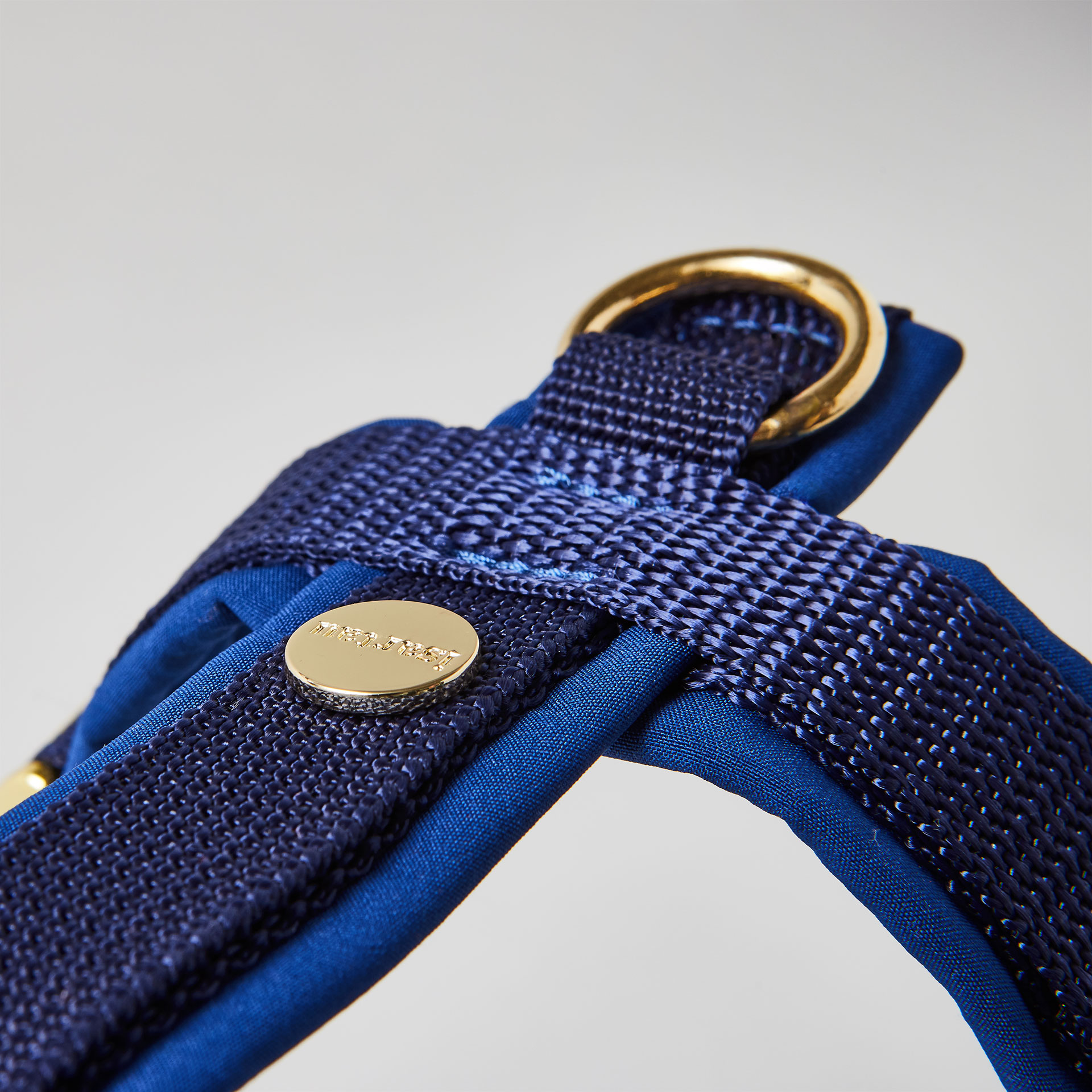 Rückenstück des dunkelblauen Hundegeschirrs mit goldfarbenem O-Ring und Logo-Niete