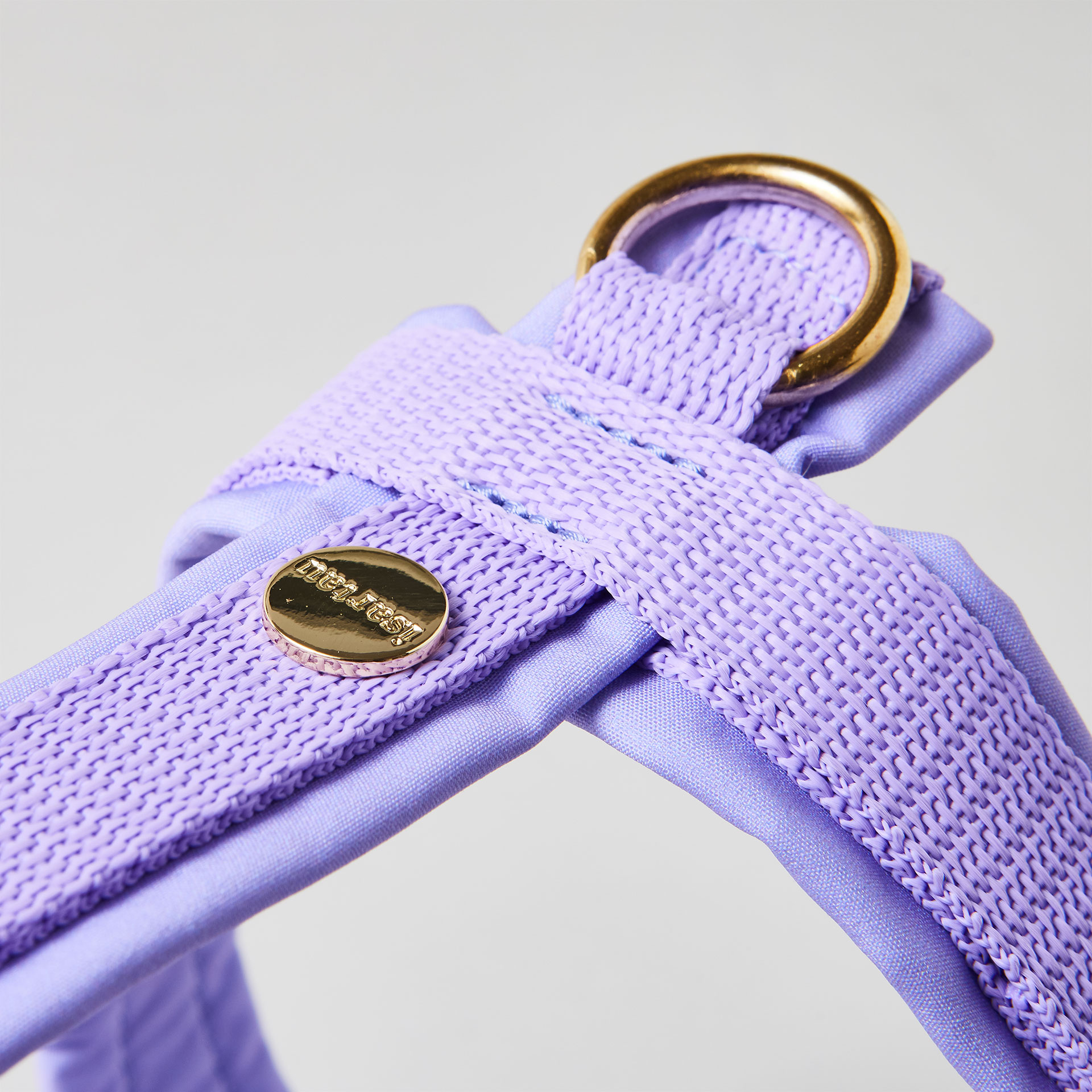 Rückenstück des lavendelfarbenen Hundegeschirrs mit goldfarbenem O-Ring und Logo-Niete