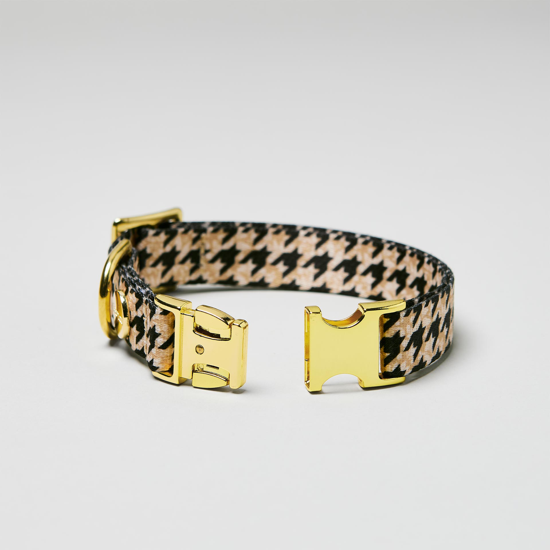 Detailaufnahme verstellbares Welpenhalsband Stadtgeflüster mit offener goldfarbener Steckschließe, Gurtband mit Hahnentrittmuster