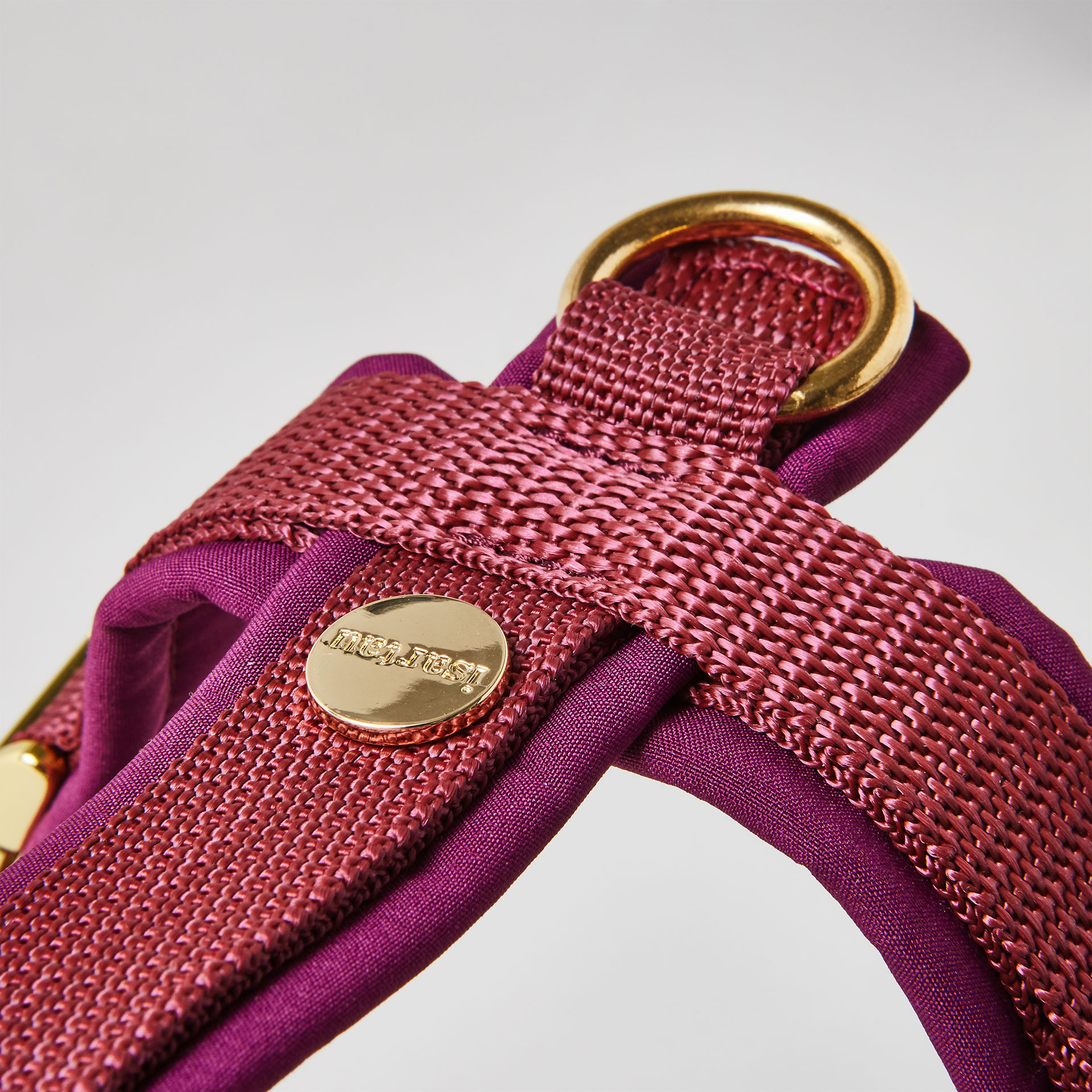 Rückenstück des burgunderfarbenen Hundegeschirrs mit goldfarbenem O-Ring und Logo-Niete