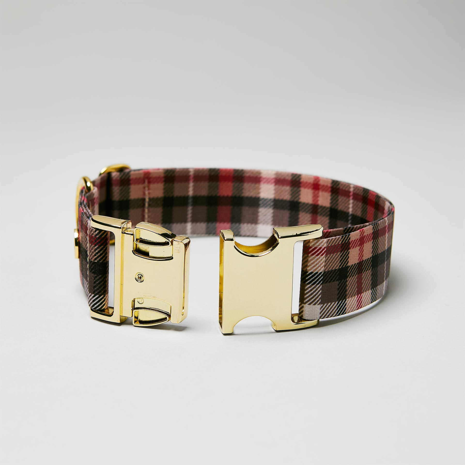 Detailaufnahme verstellbares Halsband „Flaneur“ mit geöffneter goldfarbener Steckschließe, Gurtband mit Karomuster.