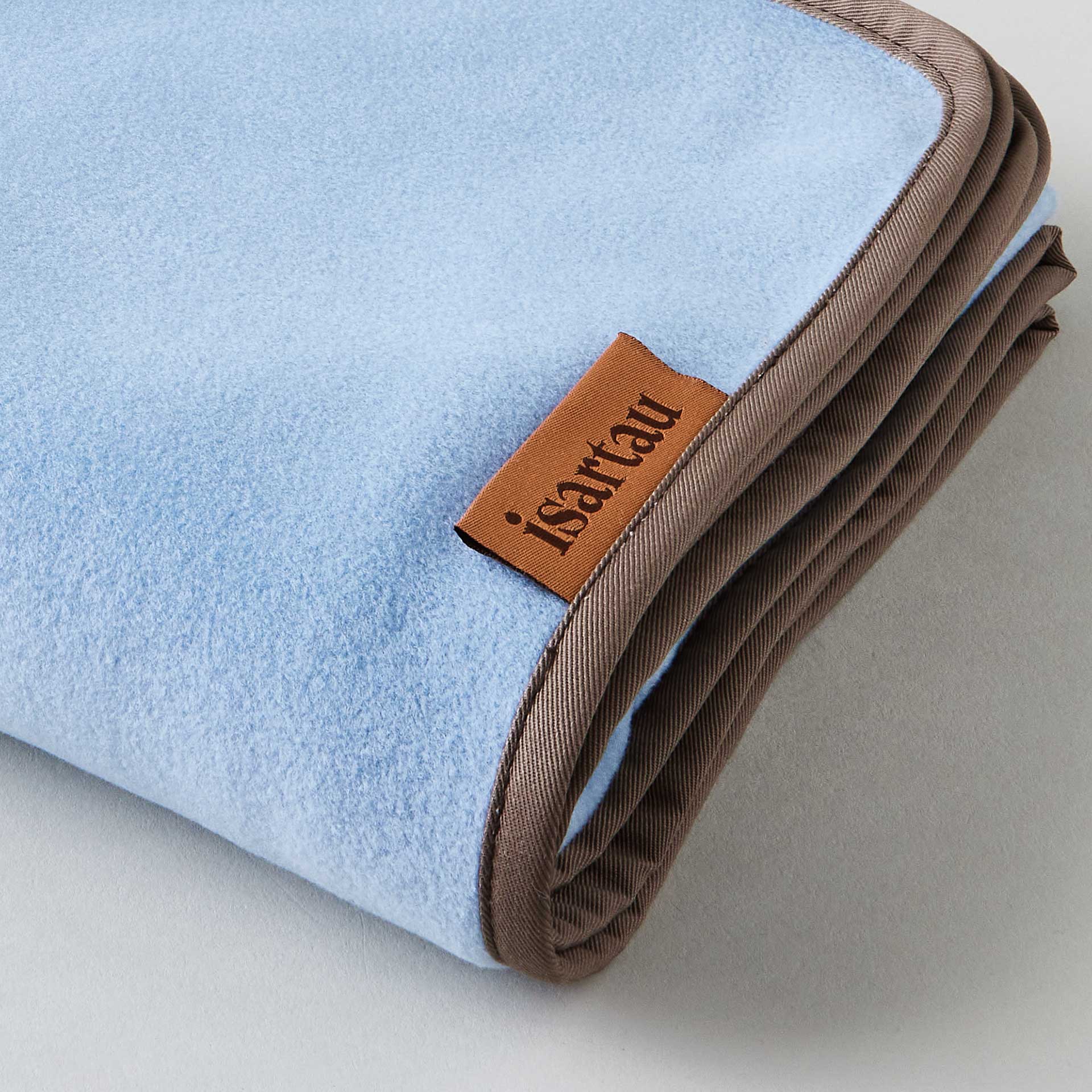 Detailbild Schmusedecke Hellblau mit beiger Einfassung, isartau Logo