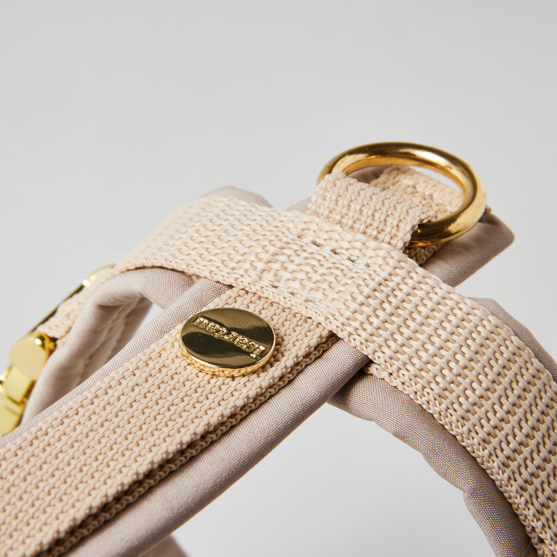 Rückenstück des beigen Hundegeschirrs mit goldfarbenem O-Ring und Logo-Niete