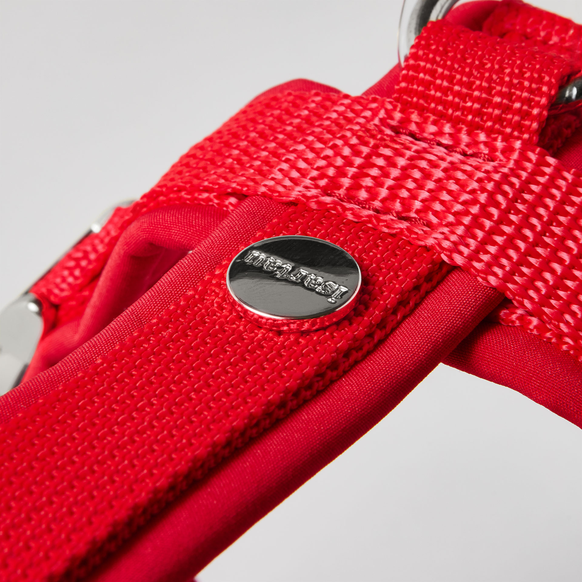 Rückenstück des roten Hundegeschirrs mit gepolstertem O-Ring zum Einhaken des Karabiners und Logo-Niete