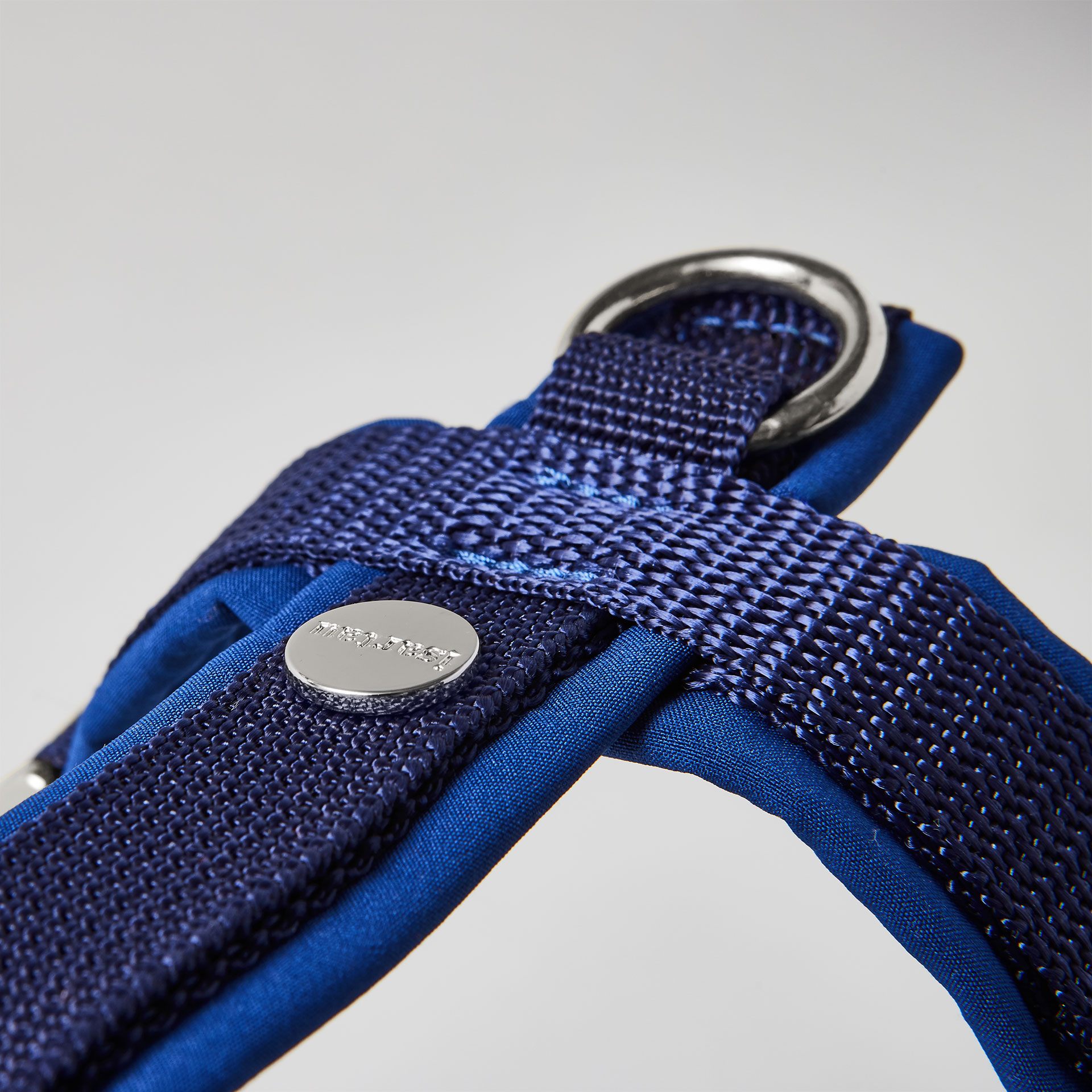 Rückenstück des dunkelblauen Hundegeschirrs mit gepolstertem O-Ring zum Einhaken des Karabiners und Logo-Niete