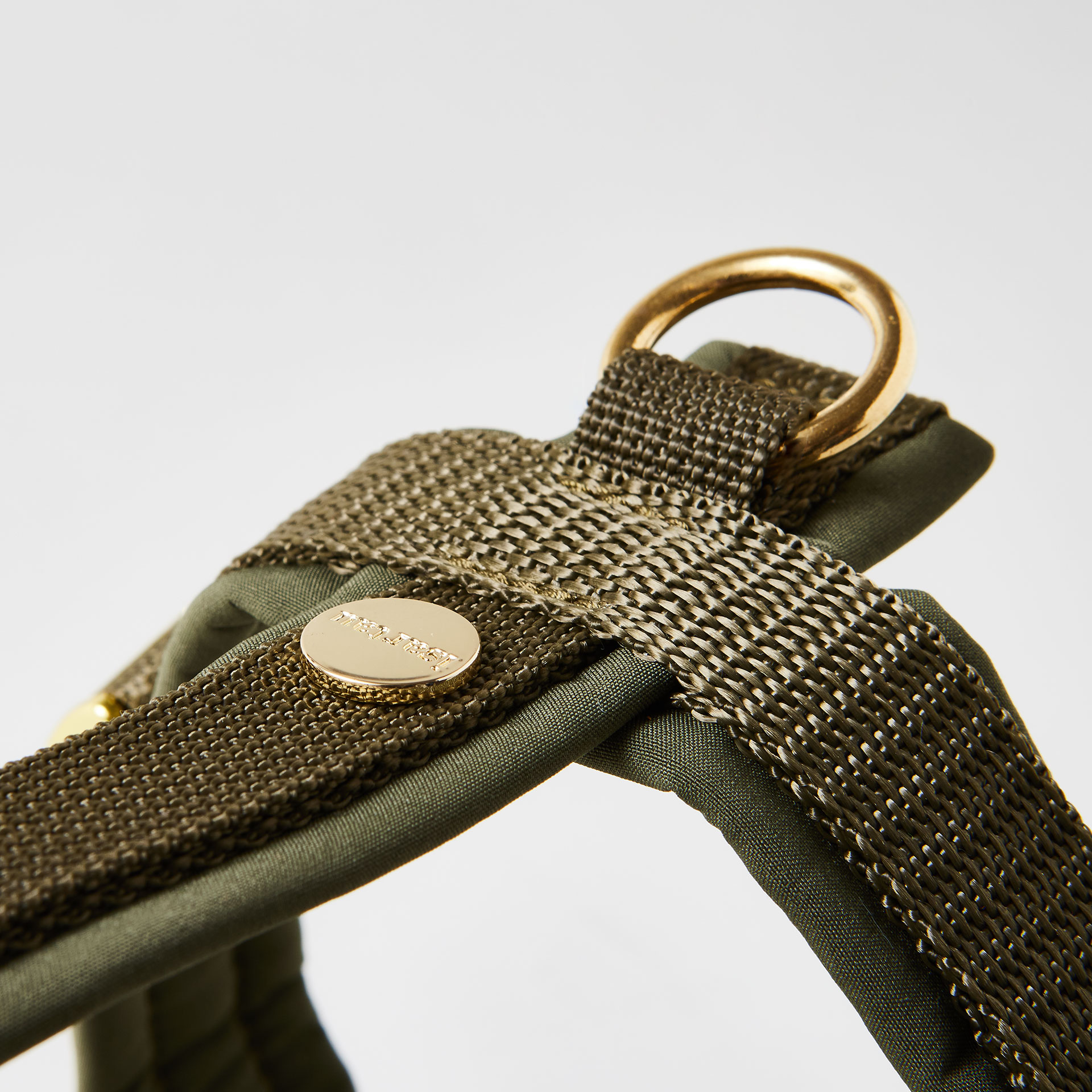Rückenstück des olivfarbenen Hundegeschirrs mit goldfarbenem O-Ring und Logo-Niete