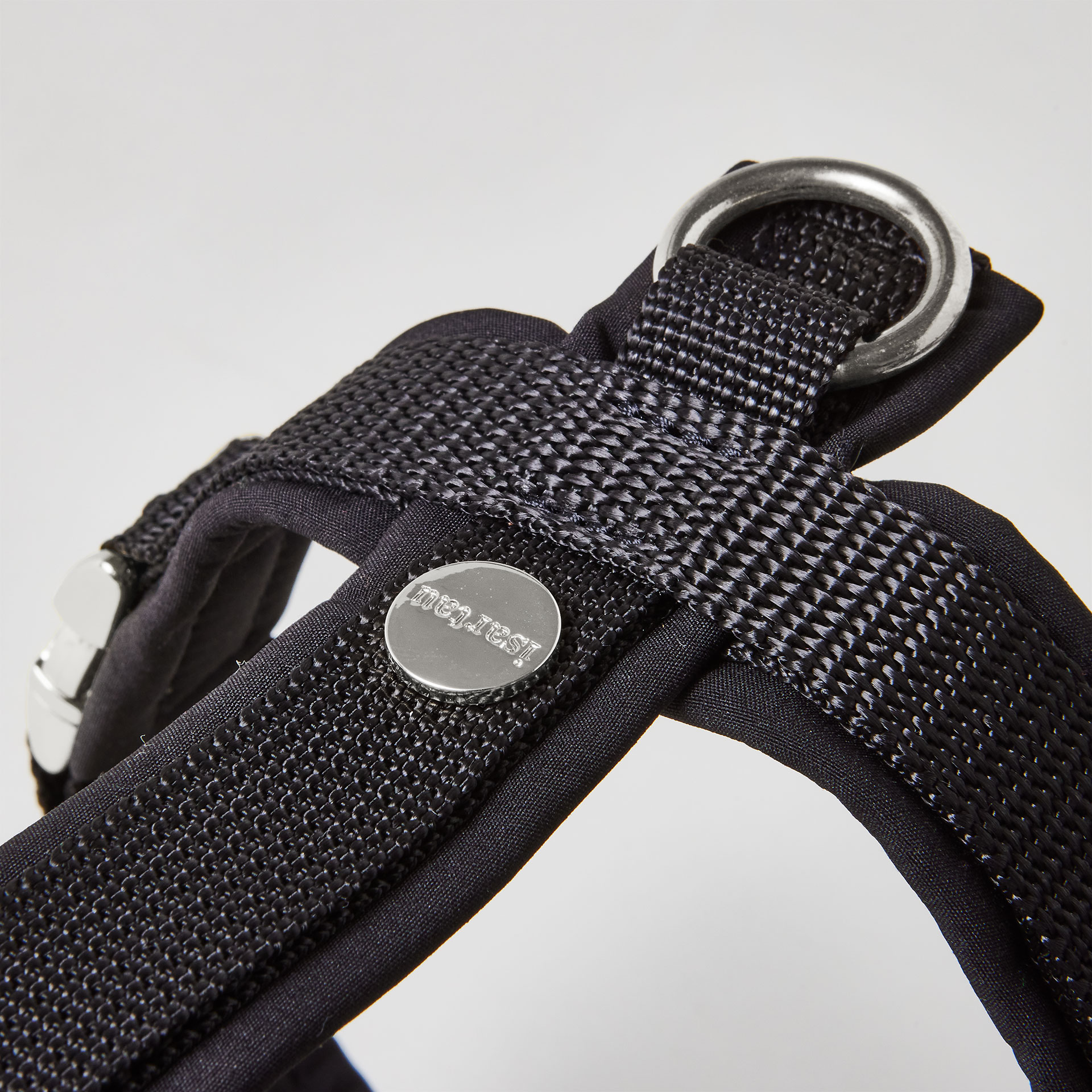 Rückenstück des schwarzen Hundegeschirrs mit gepolstertem O-Ring zum Einhaken des Karabiners und Logo-Niete