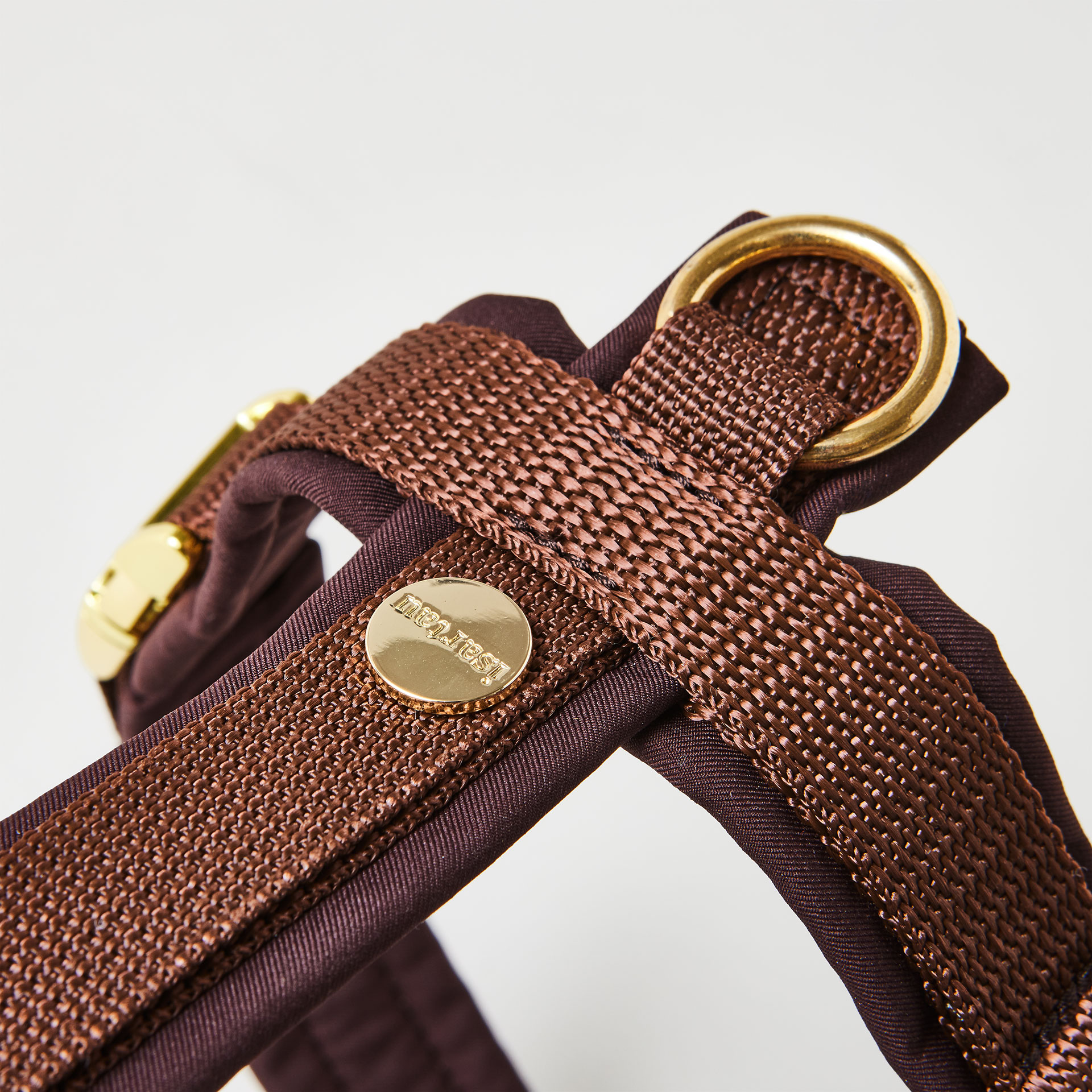 Rückenstück des dunkelbraunen Hundegeschirrs mit goldfarbenem O-Ring und Logo-Niete