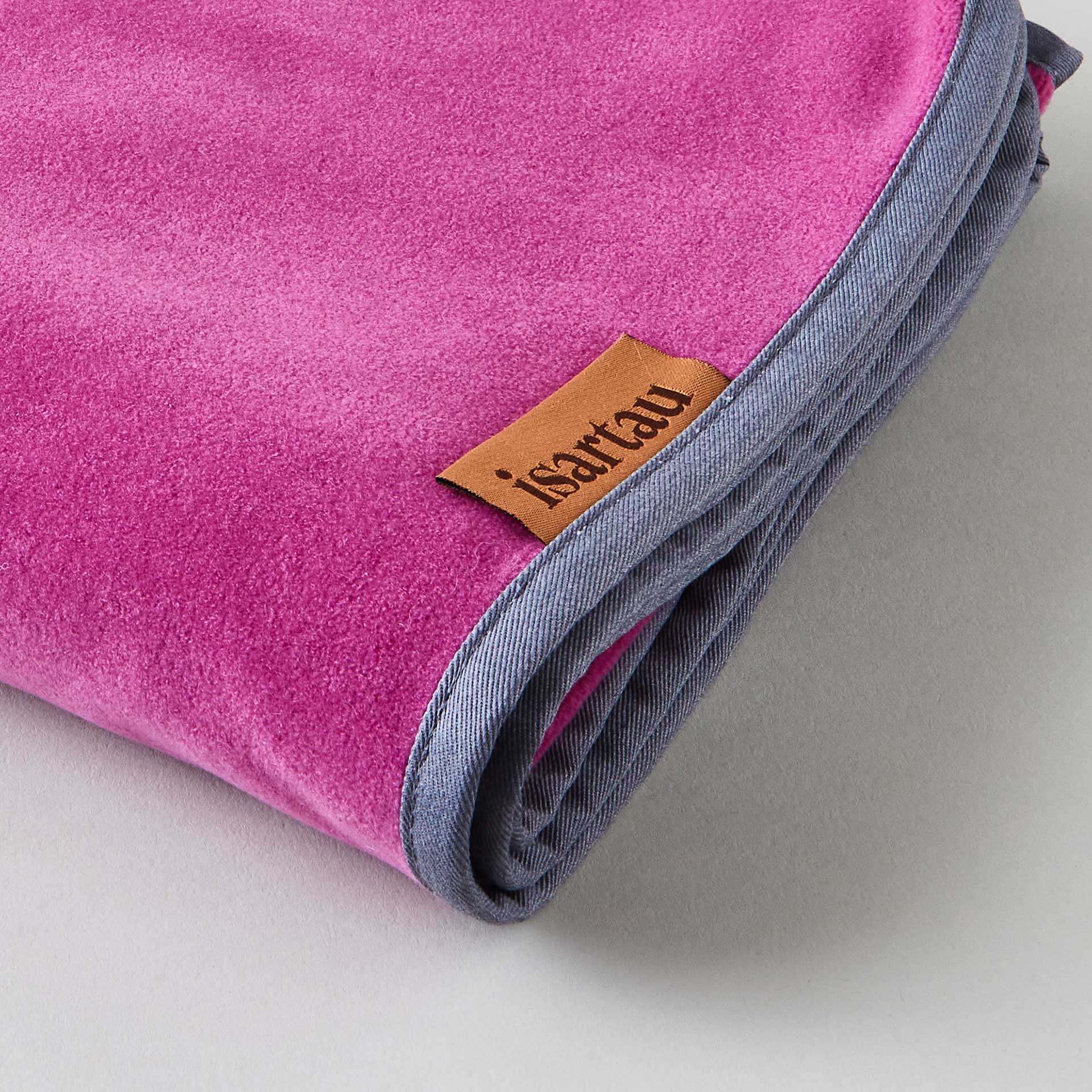 Detailbild Schmusedecke Magenta mit hellgrauer Einfassung, isartau Logo