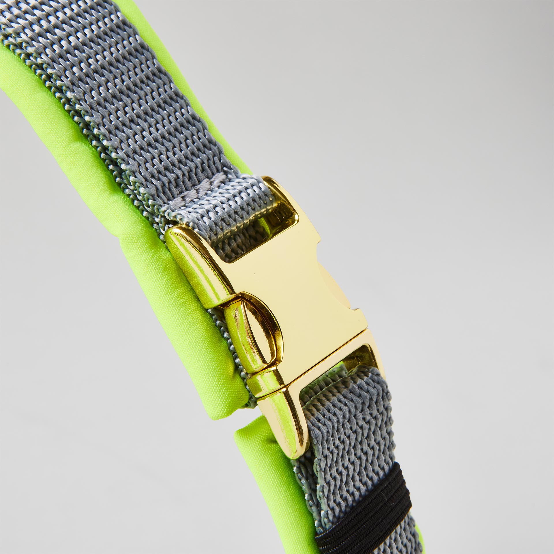 Verstellbare goldfarbene Steckschließe am grauen Bauchgurt des Hundegeschirrs Softie Neongelb Grau mit neongelber Softshell-Polsterung