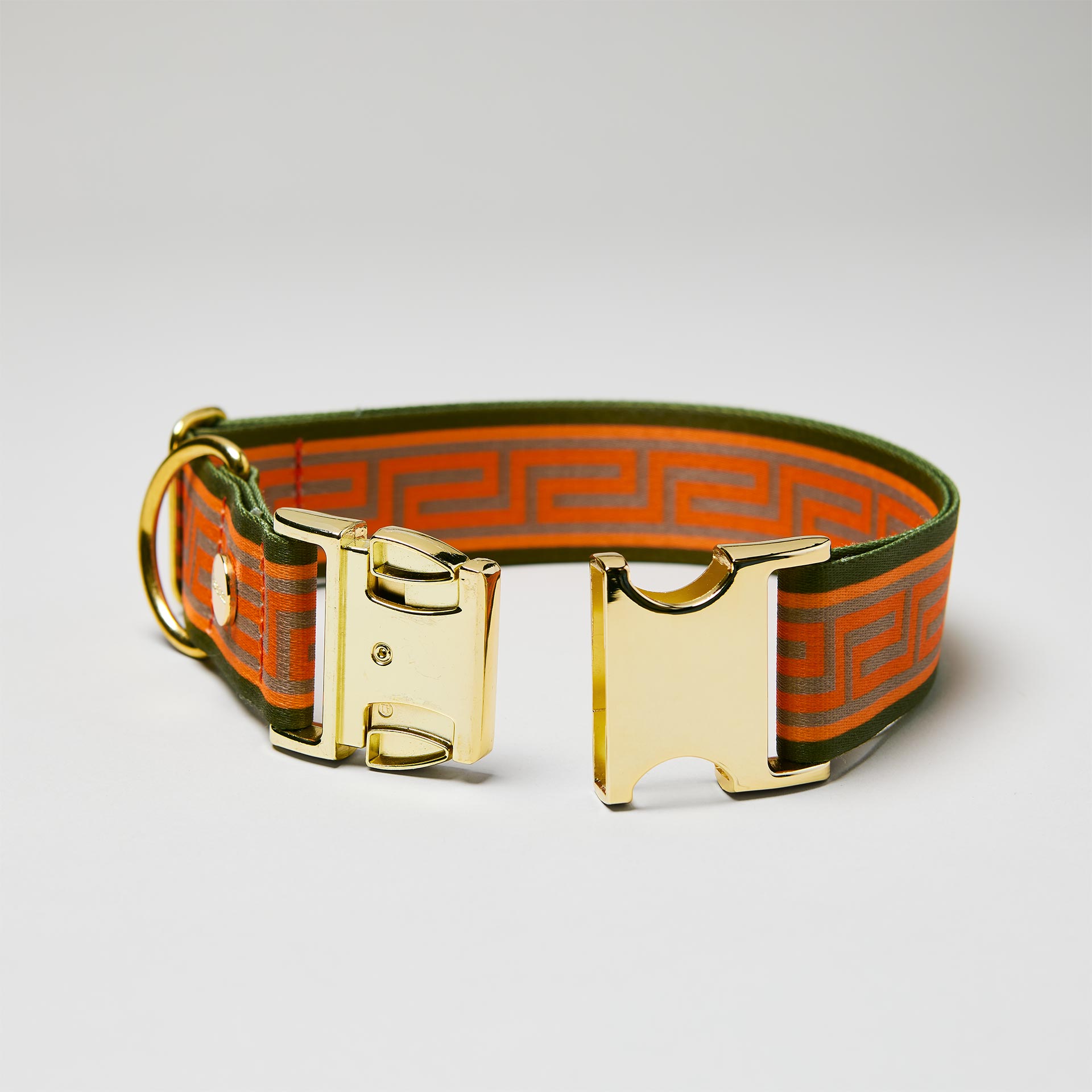 Detailaufnahme verstellbares Halsband Wellenbrecher mit offener goldfarbener Steckschließe, Gurtband mit Mäander Muster in Orange Oliv