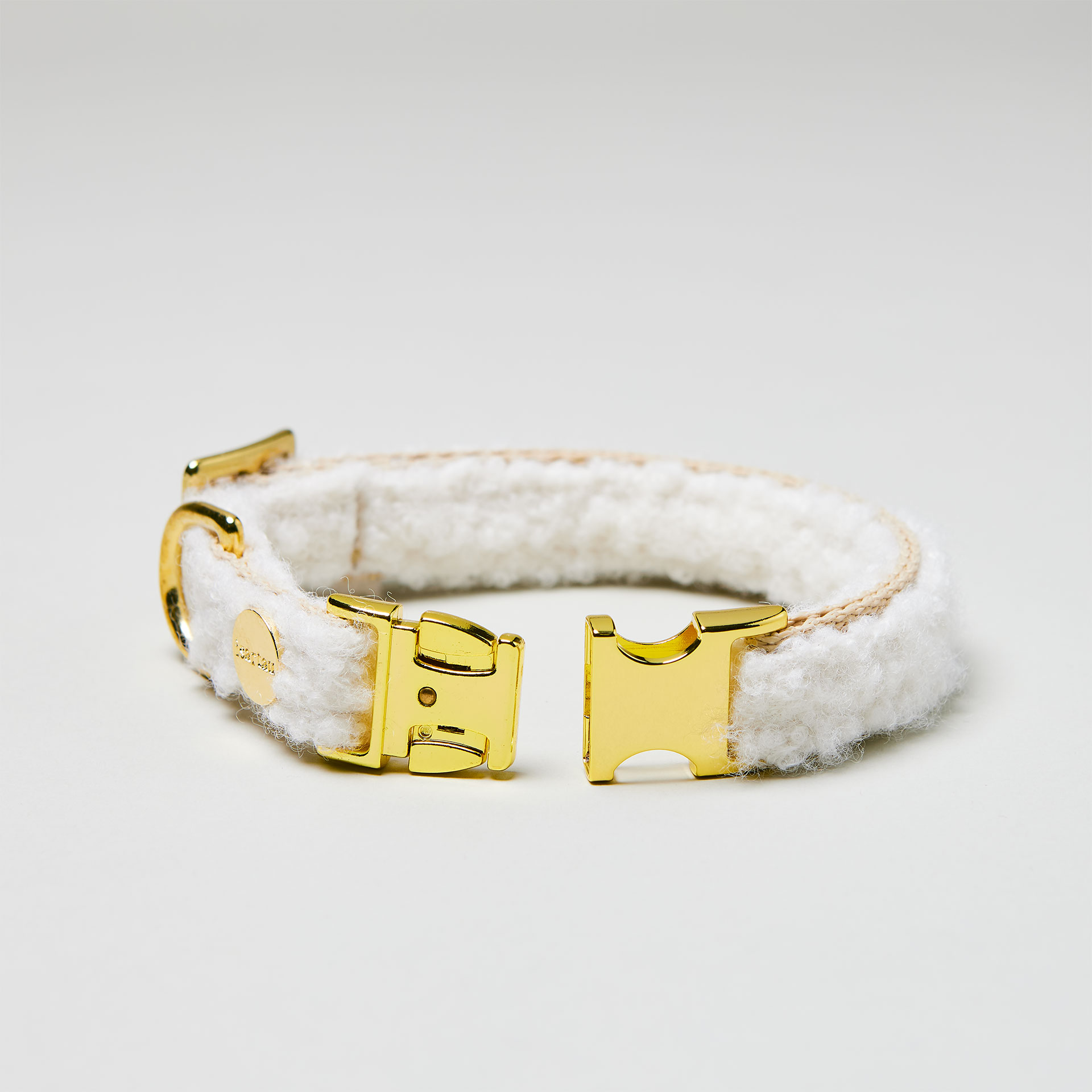Detailaufnahme verstellbares Designerhalsband Wooly mit offener goldfarbener Steckschließe, Gurtband in Beige mit weißen Bouclé Stoff