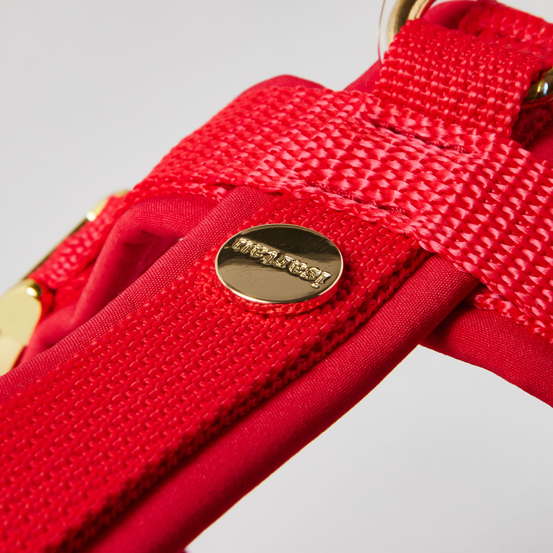 Rückenstück des roten Hundegeschirrs mit goldfarbenem O-Ring und Logo-Niete