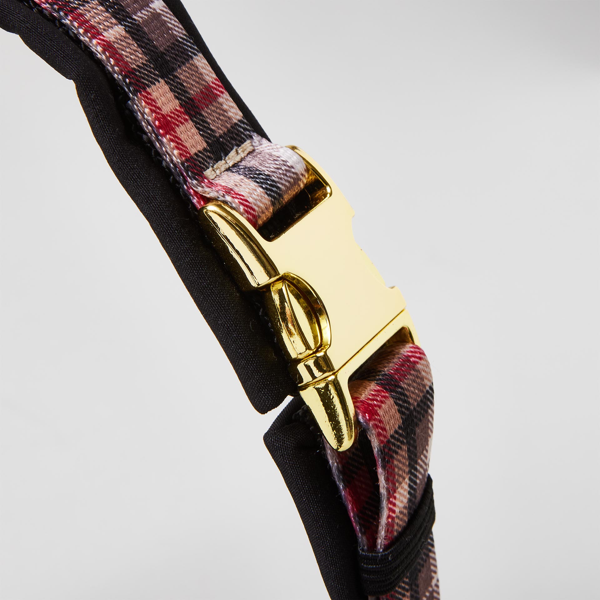 Detail gepolstertes Hundegeschirr „Flaneur“ mit goldfarbener Steckschließe zum Öffnen und Schließen, Gurtband mit Karomuster.