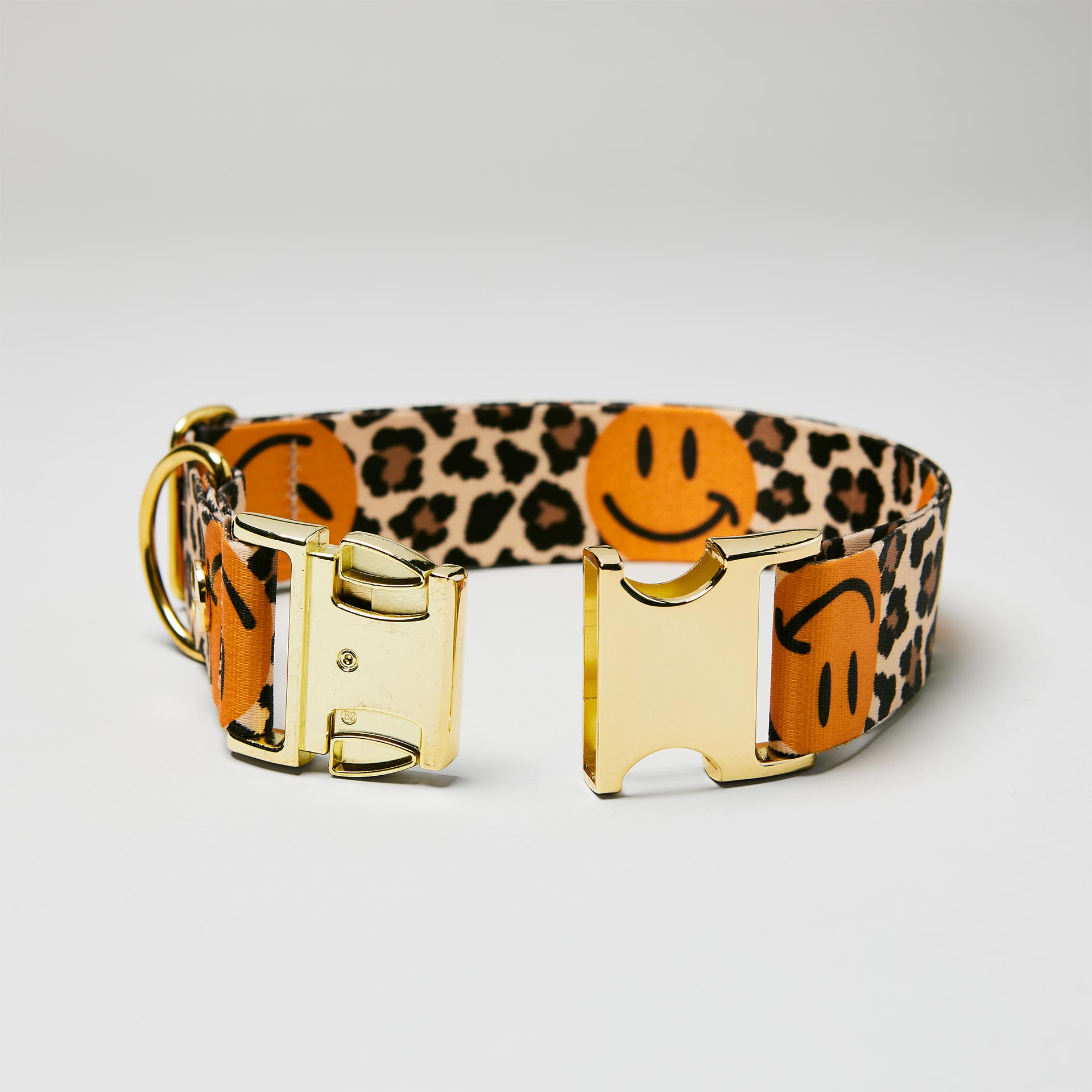 Detailaufnahme verstellbares Halsband Leo Smile mit offener goldfarbener Steckschließe, Gurtband mit Leo und Smile Motiv