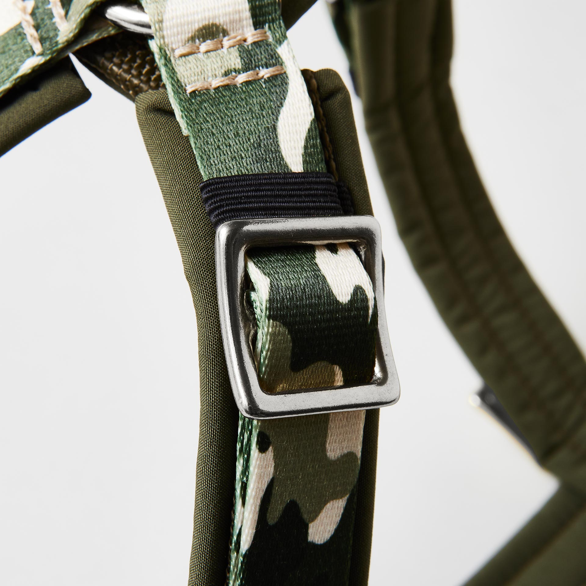 Detail verstellbares gepolstertes Hundegeschirr „Entdecker“ mit silberfarbenem Gurtbandschieber zur Größenanpassung und tarnfarbenem Gurtband.