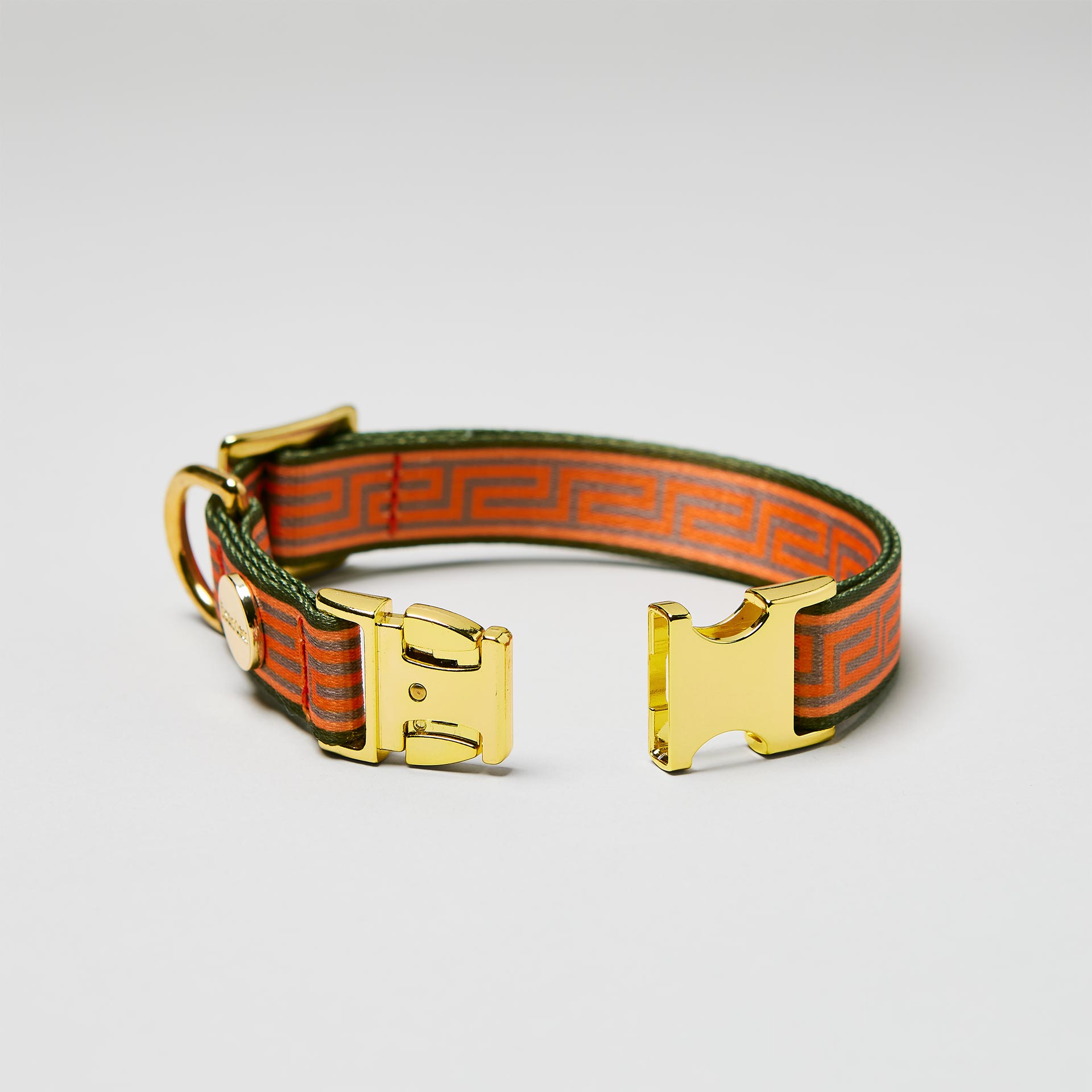 Detailaufnahme verstellbares Halsband Wellenbrecher mit offener goldfarbener Steckschließe, Gurtband im Mäander Stil