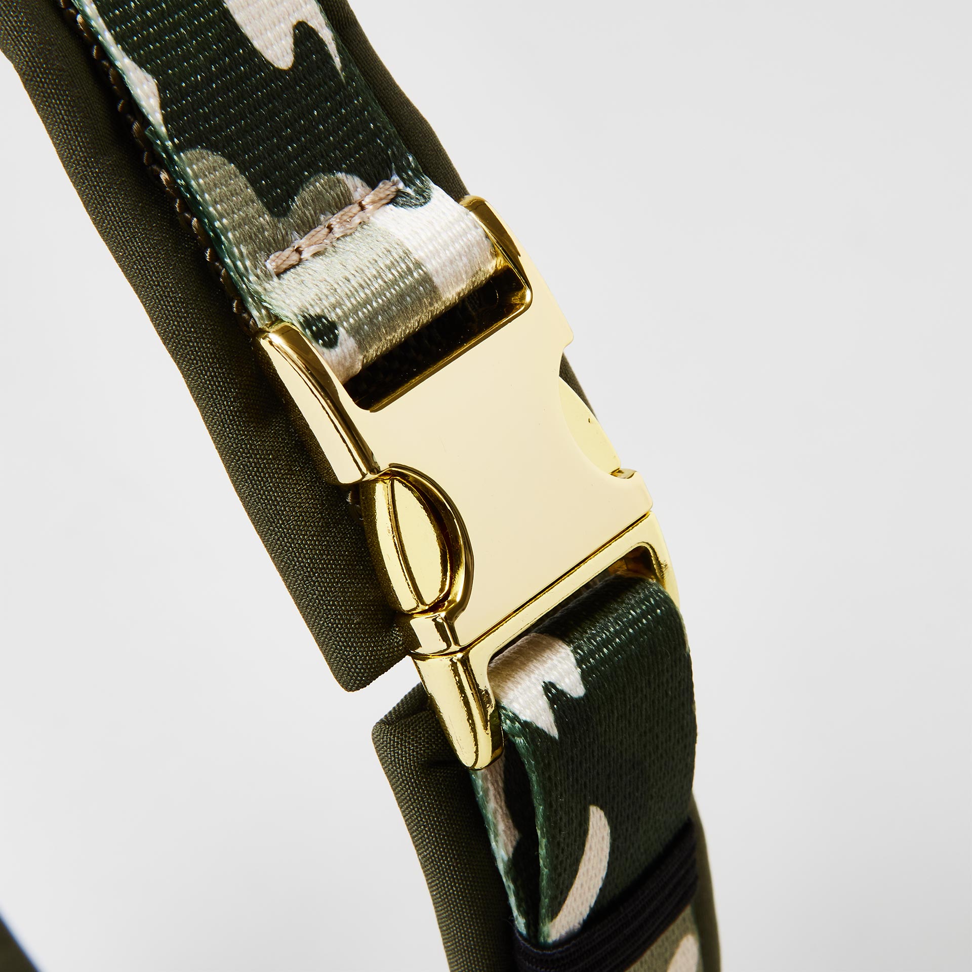 Detail gepolstertes Hundegeschirr „Entdecker“ mit goldfarbener Steckschließe zum Öffnen und Schließen, Gurtband im Camouflage-Look.