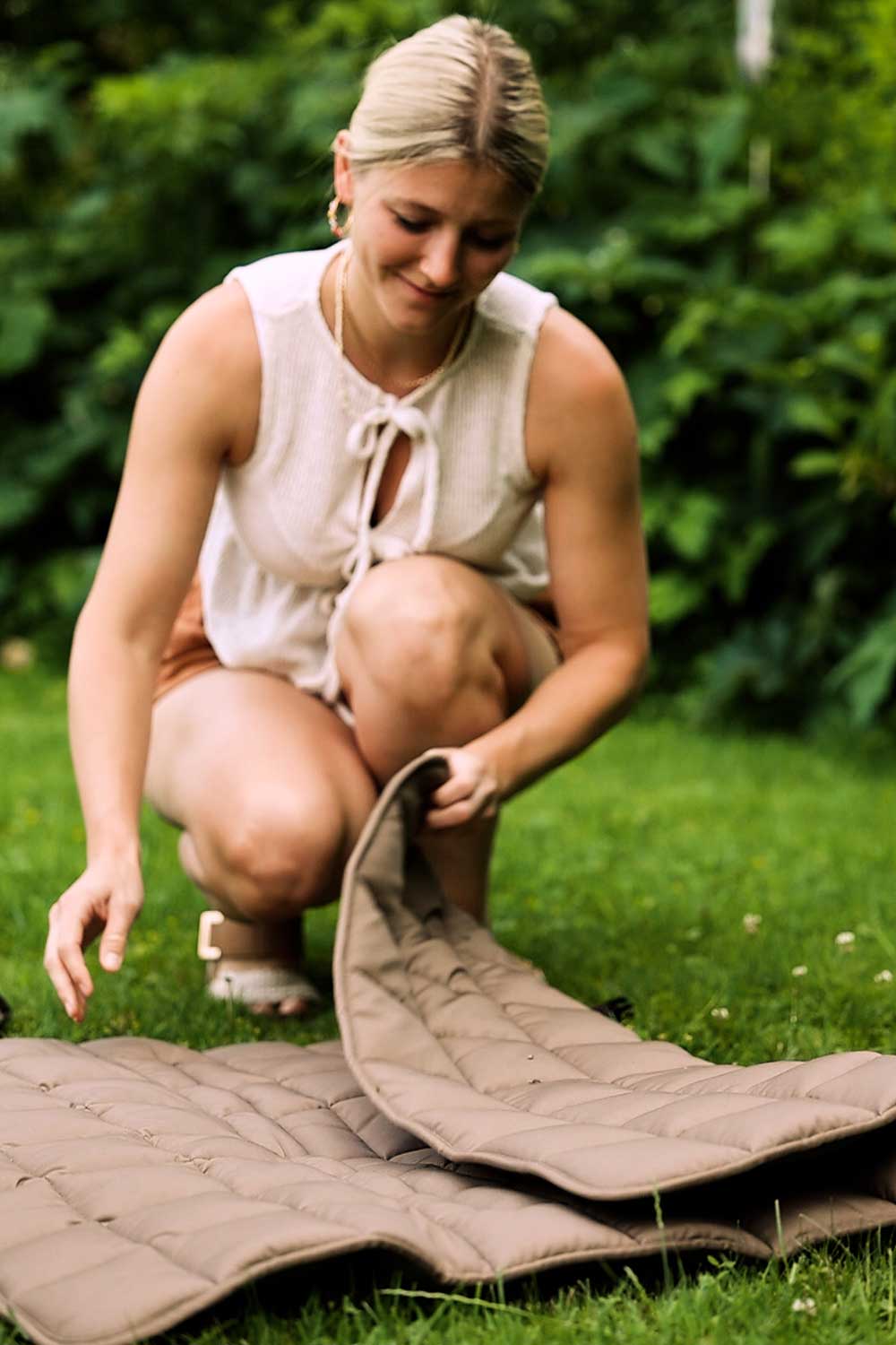 Frau klappt Reisedecke Pocket auf der Wiese auseinander